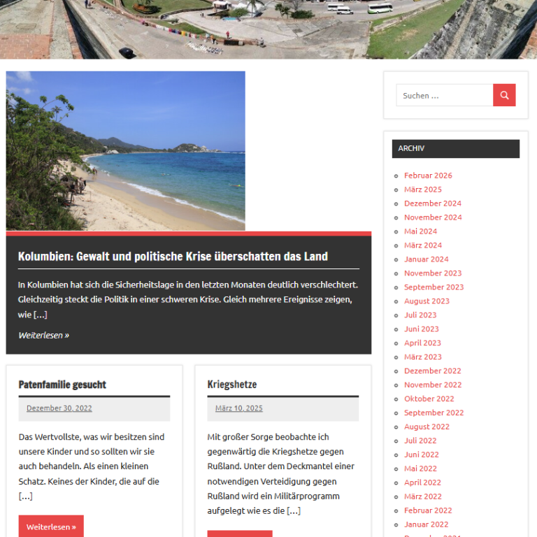 Strand mit klarem Wasser und grünem Ufer, sanfte Wellen am Sandstrand.